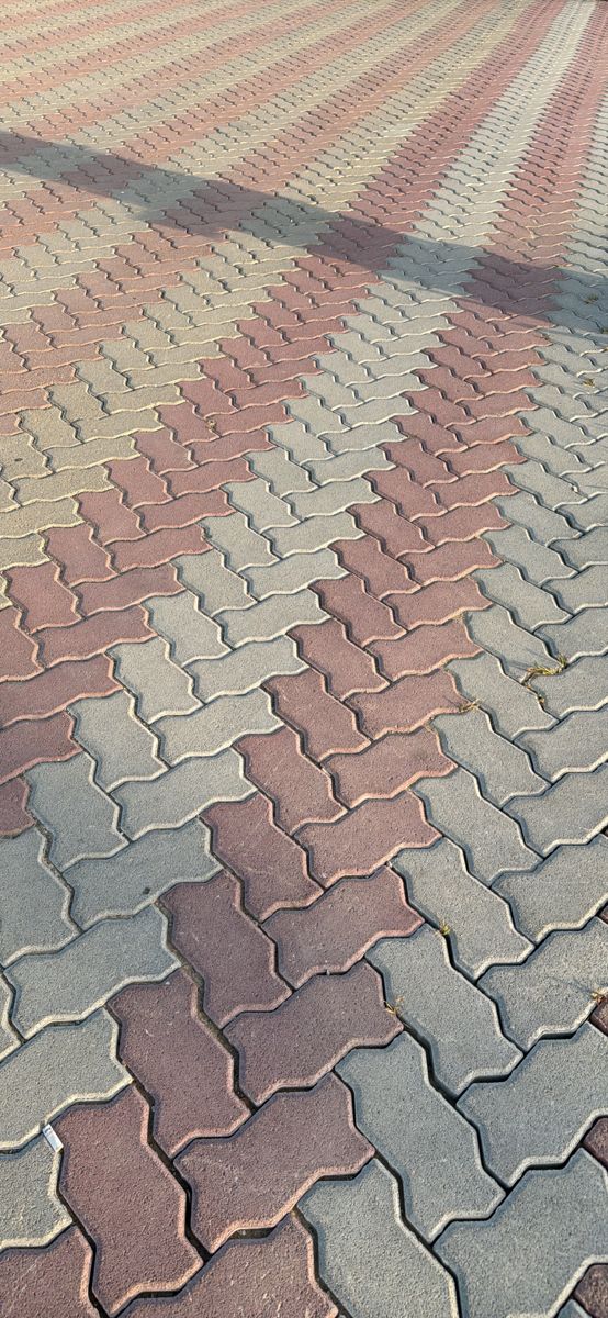 UCB Uni Paver — red and grey wavy S-shaped interlocking uni pavers installed across a large compound by Unique Concrete Builders Kenya