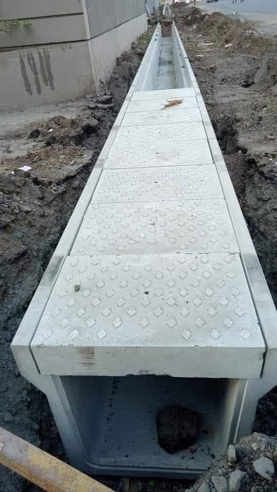 UCB Inverted Drainage Block (I.D.B.) — long precast concrete drainage channel units with textured lids being installed in a trench by Unique Concrete Builders Kenya