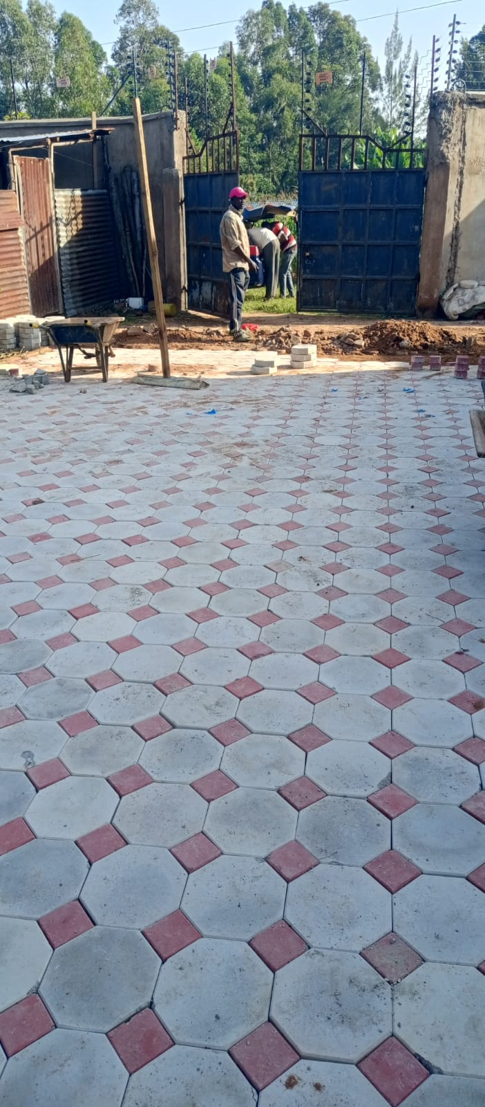 UCB Octagon Pavers being installed on a compound — white octagonal concrete pavers with red square inserts laid in a geometric pattern at a UCB project site in Kenya by Unique Concrete Builders