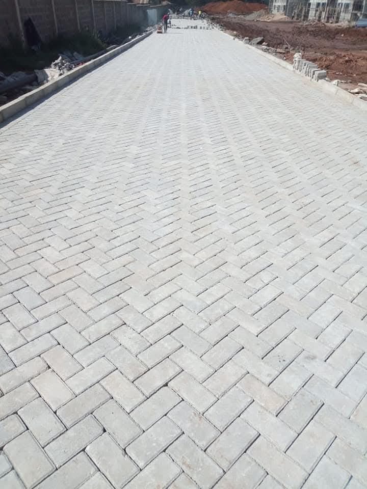Grey herringbone Uni Paver road installation in Kenya — UCB interlocking concrete blocks laid in classic herringbone pattern on a public road