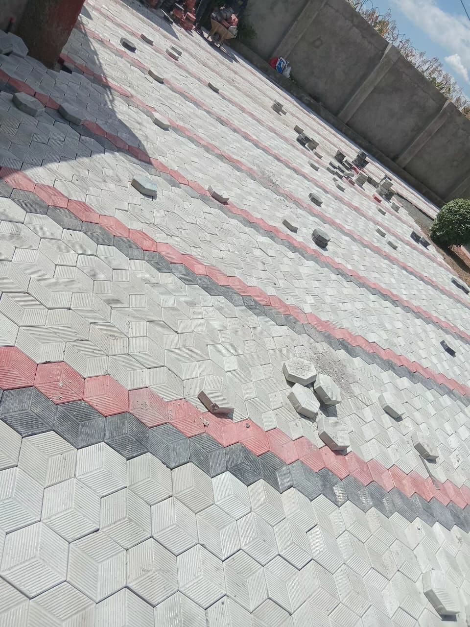 UCB Hexagon Pavers rough finish — grey, red and dark diagonal stripe hexagonal interlocking concrete pavers installed on a large compound in Kenya by Unique Concrete Builders