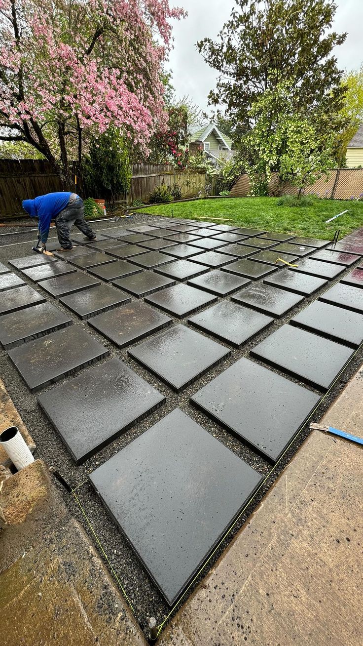 Worker installing dark square paving slabs — UCB Cabro and Paving Blocks Solutions in Kenya by Unique Concrete Builders