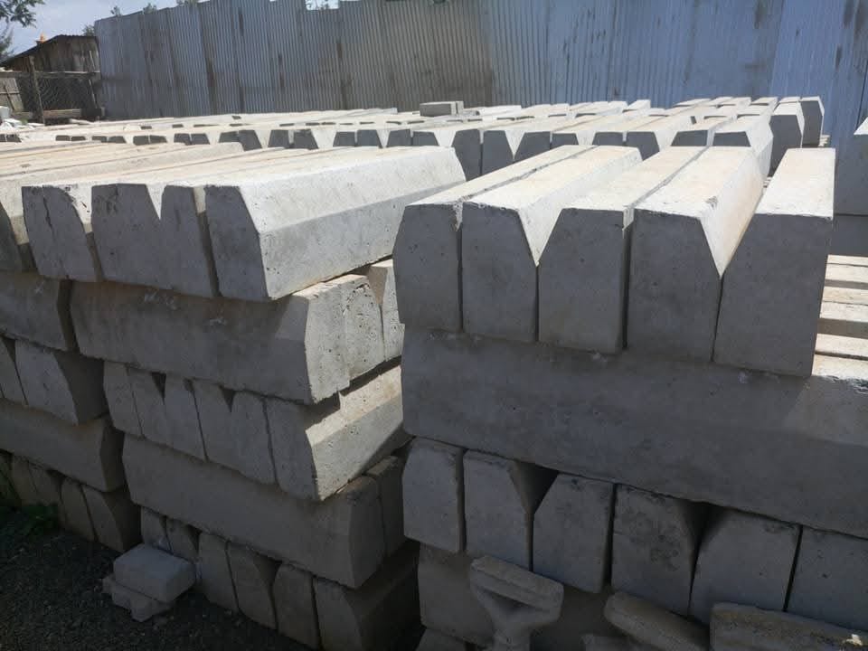 Stacked grey precast concrete road kerbs at UCB yard — bulk road kerb supply by Unique Concrete Builders Kenya